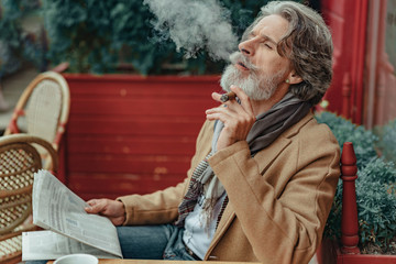 Obraz premium Elegant senior man blowing smoke out of his mouth
