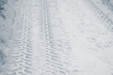 Tracktor tires on winter road covered with snow. Vehicle on snowy alley in the morning at snowfall