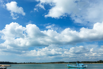 Beautiful sunny day with blue sky white clouds over the sea and fishing boat