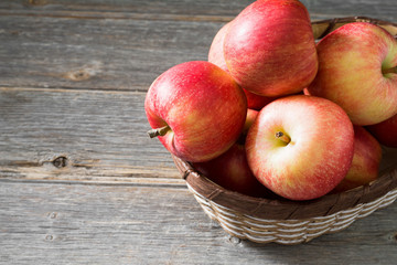 Apples in a basket on a gray wooden background. Autumn harvest