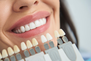 Artificial teeth locating near smiling female lips