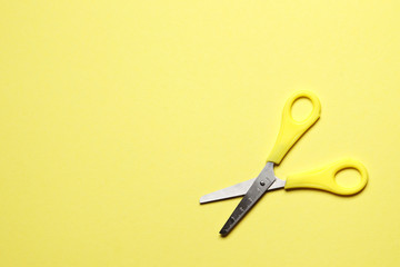 Yellow scissors on a yellow background with place for text