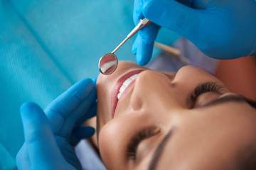 Obraz na płótnie Canvas Dentist is examining mouth of smiling woman