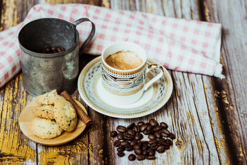 Tasse de café en porcelaine ancienne biscuits à la cannelle et grains de café sur une table en bois vintage	