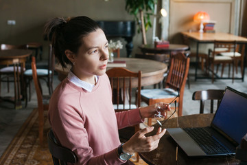 Site development. An excited girl in a pink sweater with dark hair sits at an old desk in the...