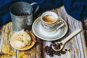 Tasse de café en porcelaine ancienne biscuits à la cannelle et grains de café sur une table en bois vintage	