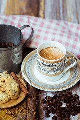 Tasse de café en porcelaine ancienne biscuits à la cannelle et grains de café sur une table en bois vintage	