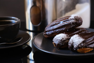 three chocolate eclairs on a plate and cup of coffee. traditional fcench Chocolate Eclairs