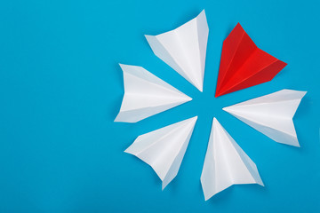 Group of white paper plane in one direction and one red paper plane pointing in different way on blue background. Business for innovative