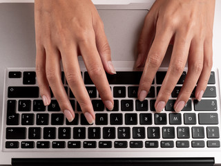 Fototapeta na wymiar Top view of a woman's hands typing on a computer keyboard