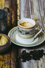 Tasse de café en porcelaine ancienne biscuits à la cannelle et grains de café sur une table en bois vintage	