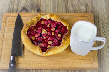 pie with raspberry and mug of milk on a wooden background