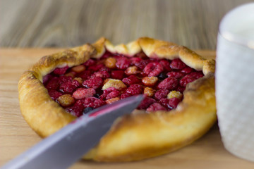 pie with raspberry and mug of milk on a wooden background