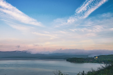 Mountain lake and valley shrouded in fog in the rays of dawn