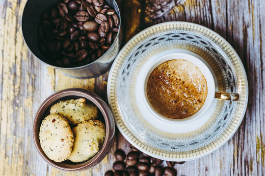 Tasse de café en porcelaine ancienne biscuits à la cannelle et grains de café sur une table en bois vintage © PicsArt