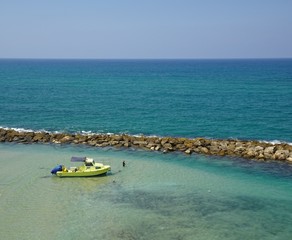 Boat taking protection behind breakwater while guy fishes