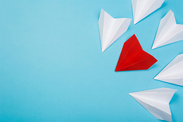 Group of white paper plane in one direction and one red paper plane pointing in different way on blue background. Business for innovative