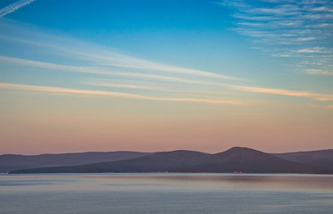 Dawn over the lake in the old mountains of the southern Urals. Fog above the water and among the wooded hills, colored by the rays of the rising sun