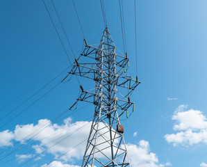 high voltage tower against the blue sky and clouds