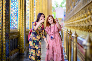 young tourist women walking and enjoy looking the palace temple in Bangkok of Thailand, Emerald...