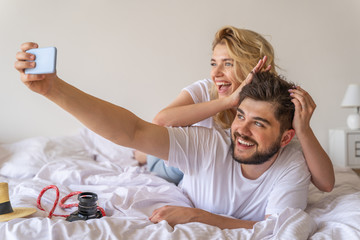 Obraz na płótnie Canvas Smiling couple in love making selfie in bed