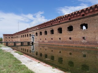Fototapeta premium Side view of the front of Fort Jefferson, Dry Tortugas National Park in Florida, with the fort reflected in the moat waters.