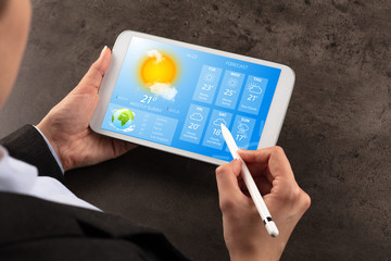 Business woman checking weekly weather forecast on tablet