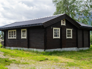 Fototapeta na wymiar Traditional Brown Wooden Scandinavian House with White Windows at a Camping on the green lawn