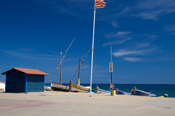 waterfront with a small blue house, flag and boats