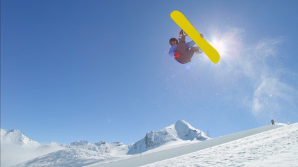 Fototapeta premium Young pro snowboarder jumping over the sun in half pipe snow park