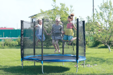 children jumping on a trampoline, girlfriends having fun in the summer in a recreation park on a trampoline - obrazy, fototapety, plakaty