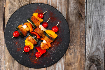 Raw shashliks on black stone plate