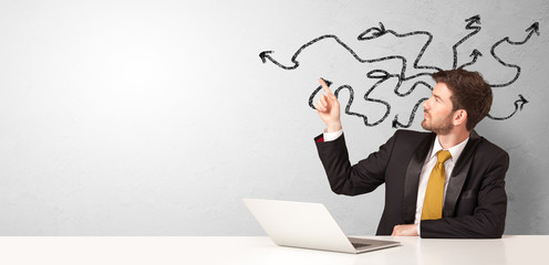 Businessman sitting at desk with direction concept