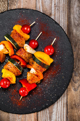 Raw shashliks on black stone plate