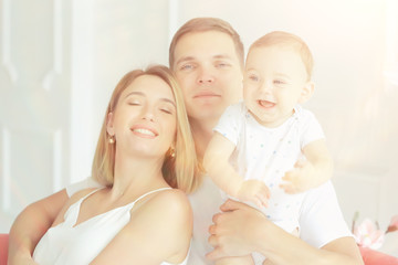 baby with parents in a cozy house / healthy young family mom dad and baby, happiness smile
