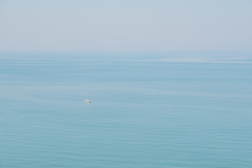 Naklejka premium Calm blue sea fusing with skies. Peaceful and tranquil marine view, a small boat passing by.