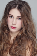 Fototapeta premium Portrait of young beautiful girl with clean makeup and long curly hair