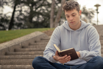 Christian worship and praise. A young man is praying and reading the bible in the evening.