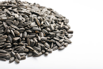 Seeds in a black shell are a bunch on a white background. In full screen