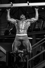 Fototapeta na wymiar Muscular Men Performing Chin-Ups at the Gym. Blask and White Image