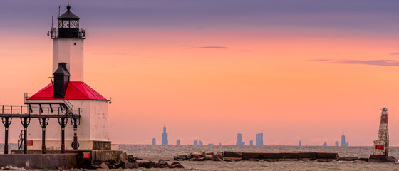 Michigan City, Indiana / USA 05/21/2019: Lighthouse During golden Hour with Chicago in the background. - obrazy, fototapety, plakaty