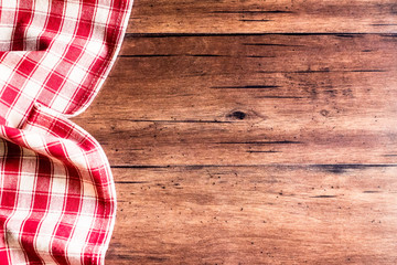 Checkered red napkin on an old wooden brown background, top view. Image with copy space. Kitchen table with a towel - top view with copy space. 