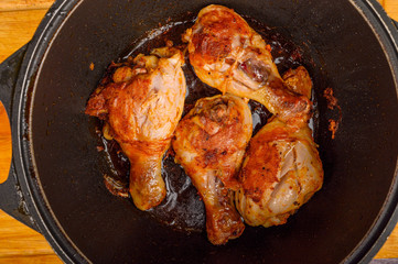 Chicken legs marinated with spices are fried in a cauldron