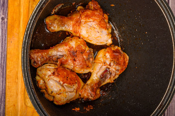 Chicken legs marinated with spices are fried in a cauldron