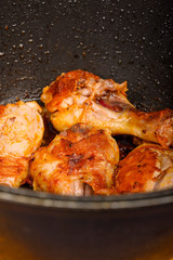 Chicken legs marinated with spices are fried in a cauldron