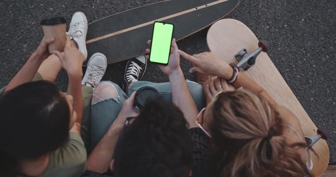 Teenage friends look at green screen phone