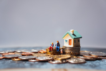 Miniature people, man and woman sitting on stack coins using as business and life success concept