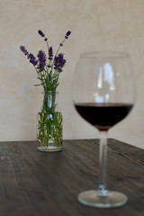 high size blurred glass red wine on a dark brown table with lavender branch in background