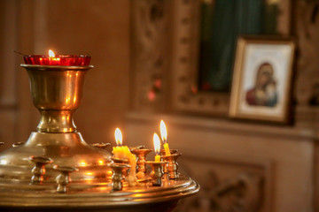 church candles burn in the temple on the background of the icon