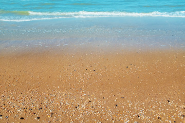 Sanfte Welle am goldenen Sandstrand mit blauem Wasser